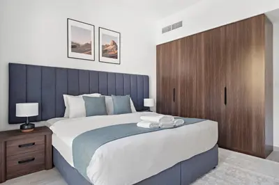 a bedroom with a large bed with a wooden headboard at StoneTree - Furnished 1BR in Madinat Jumeirah in Dubai