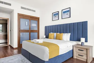 a large bed with a blue headboard in a bedroom at Luxury 1BR - Leisure Facilities Access - Sea View in Dubai