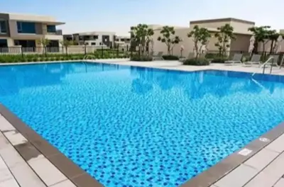 a large blue swimming pool in front of a building at Oraya - Brand New Luxurious 3BR plus 2M Villa in Maple 2 in Dubai