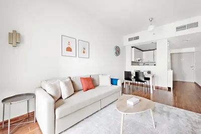 a white living room with a couch and a table at StoneTree - Furnished 1BR in JLT with Lake View in Dubai