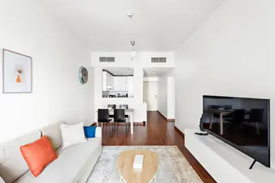 a living room with a couch and a large tv at StoneTree - Furnished 1BR in JLT with Lake View in Dubai
