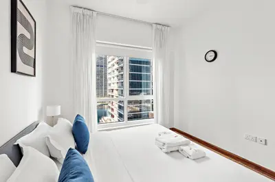 a white room with a large window and a couch at StoneTree - Furnished 1BR in JLT with Lake View in Dubai