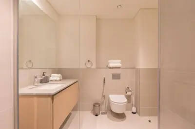 a bathroom with a toilet and a sink and a shower at Creek Beach Roomy 3BR + terrace in Dubai
