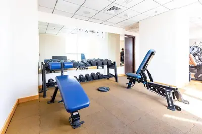 a gym with a row of treadmills and blue chairs at Your Cosy Marina Retreat in Dubai