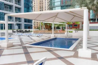 a large white umbrella over a pool in a city at Your Cosy Marina Retreat in Dubai