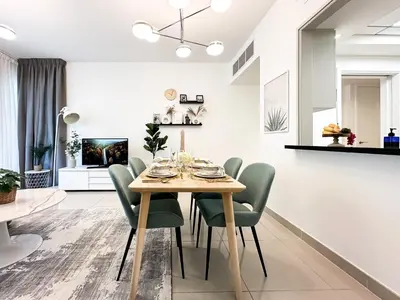 a dining room with a wooden table and green chairs at Trophy - 29 Boulevard Tower Downtown Suite in Dubai