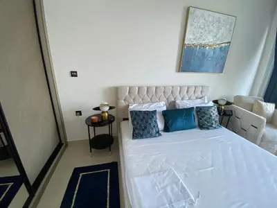 a bedroom with a white bed with blue pillows at White and gold studio apartment in Binghatti Canal whit pool in Dubai