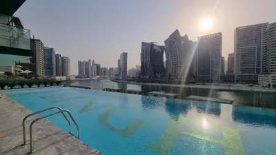 a large swimming pool in a city with tall buildings at White and gold studio apartment in Binghatti Canal whit pool in Dubai
