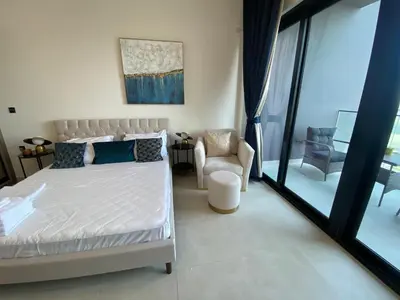 a bedroom with a white bed and a chair at White and gold studio apartment in Binghatti Canal whit pool in Dubai