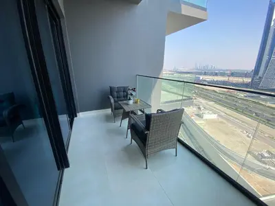 a room with chairs and a table and a large window at White and gold studio apartment in Binghatti Canal whit pool in Dubai