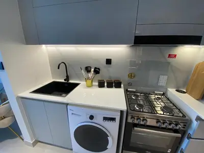 a small kitchen with a stove and a sink at White and gold studio apartment in Binghatti Canal whit pool in Dubai
