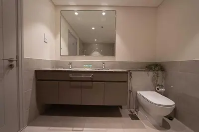 a bathroom with a toilet and a sink and a mirror at Oraya - Chic 2BR Apt in Downtown Dubai With City Views in Dubai
