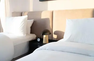 two beds with white sheets and a lamp on a night stand at Oraya - Chic 2BR Apt in Downtown Dubai With City Views in Dubai