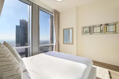 a bedroom with a white bed and a large window at Visionary Vista: 2BR Al Habtoor City in Dubai