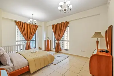 a bedroom with a large bed and two windows at Cozy pad in the heart of Dubai on JBR beach! in Dubai