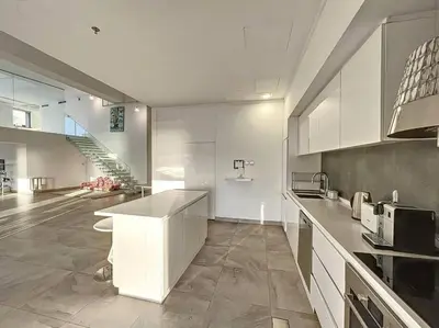 a large kitchen with white cabinets and a staircase at Rimal 3 - Incredible Two Bedroom in Dubai