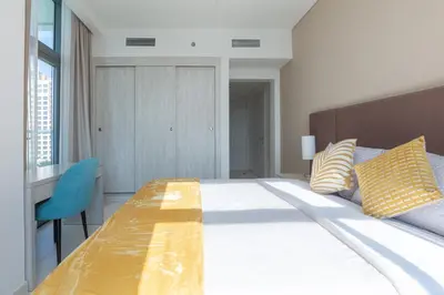 a bedroom with a large bed and a blue chair at Seven Palm, Private beach, Infinity Pool, High Floor 3BDR in Dubai