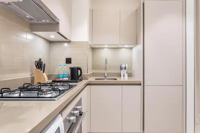 a white kitchen with a stove and a sink at STAY BY LATINEM Luxury 1BR Holiday Home CVR A1504 near Burj Khalifa in Dubai