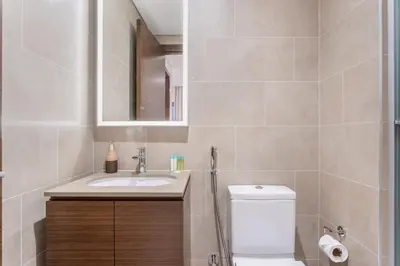 a bathroom with a toilet and a sink and a mirror at STAY BY LATINEM Luxury 1BR Holiday Home CVR A1504 near Burj Khalifa in Dubai