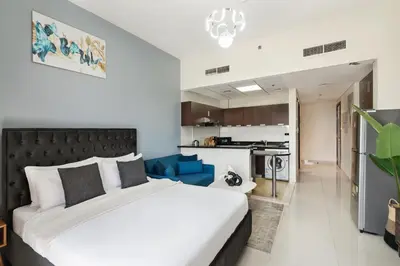 a bedroom with a large bed and a kitchen at Modern Studio Sports City Pool & City Views in Dubai