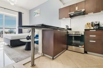 a kitchen with a table and a living room at Modern Studio Sports City Pool & City Views in Dubai