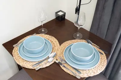 a table with blue plates and wine glasses on it at Modern Studio Sports City Pool & City Views in Dubai