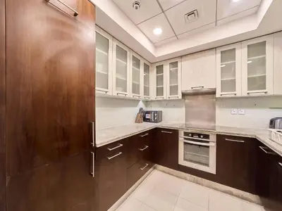 a kitchen with wooden cabinets and a stainless steel refrigerator at Golden Homes Boulverd Central 1BHK BLUE HEAVEN Near Dubai mall & burj khalifa Downtown Dubai in Dubai