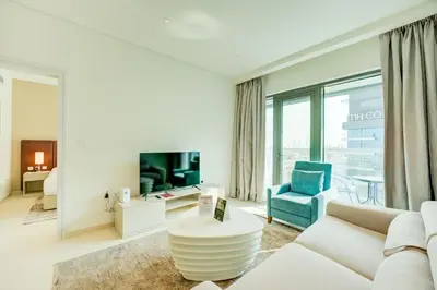 a living room with a white couch and a blue chair at Seven Palm 1 Bed with Rooftop Infinity Pool in Dubai
