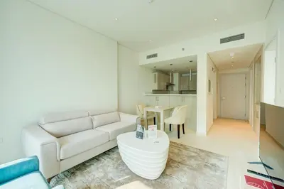 a living room with a white couch and a table at Seven Palm 1 Bed with Rooftop Infinity Pool in Dubai