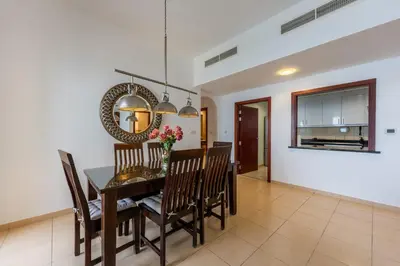 a dining room with a table and chairs and a mirror at JBR High Floor 2 Bed with full Al Ain View in Dubai