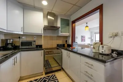 a kitchen with white cabinets and a microwave at JBR High Floor 2 Bed with full Al Ain View in Dubai