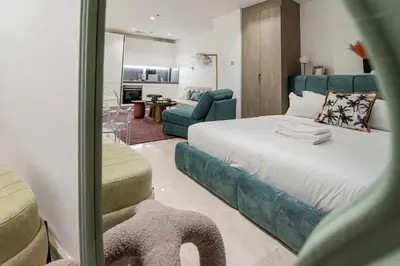 a bedroom with a large bed and a living room at Designer Glam Studio Steps from Burj Khalifa in Dubai