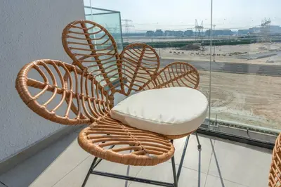 a wicker chair sitting in front of a window at Studio 12min from Burj Khalifa - Azizi Riviera 32 - Dubai in Dubai