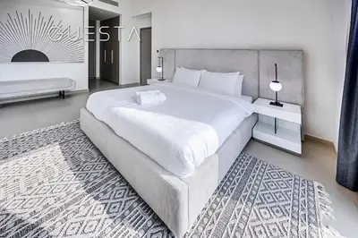 a white bedroom with a large white bed and a rug at Act One Act Two by Emaar, Downtown Dubai in Dubai