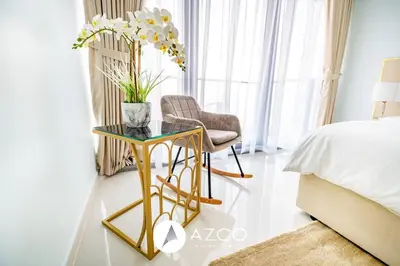 a bedroom with a gold side table and a chair at 1BR Apartment in Paramount Midtown in Dubai