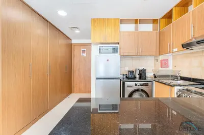 a kitchen with wooden cabinets and a refrigerator at Comfortable Studio at Lago Vista A Dubai Production City by Deluxe Holiday Homes in Dubai