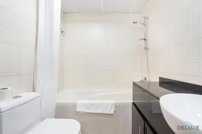 a bathroom with a tub and a toilet and a sink at Comfortable Studio at Lago Vista A Dubai Production City by Deluxe Holiday Homes in Dubai