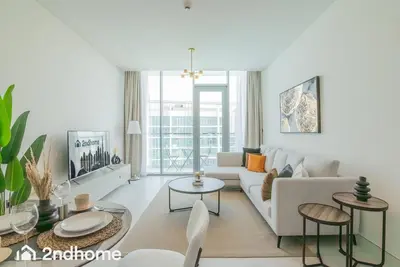 a white living room with a white couch and tables at 2ndHome - District One Residences , Residence 14 in Dubai