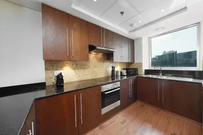 a kitchen with wooden cabinets and a large window at Discover unmatched Comfort in Downtown Dubai in Dubai