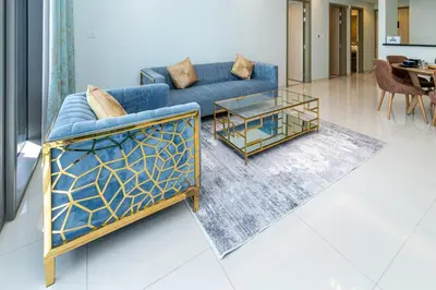 a living room with a blue couch and a table at Stylish 2BR Retreat Wi-Fi & Pool Access in Dubai