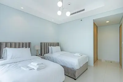 two beds in a bedroom with white walls at Stylish 2BR Retreat Wi-Fi & Pool Access in Dubai