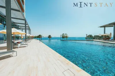 a swimming pool with chairs and umbrellas next to a building at Bluewaters Residences 5, Bluewaters Island - Mint Stay in Dubai