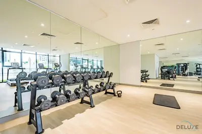 a gym with rows of treadmills and machines at Decent 1BR at Azizi Riviera 17, Al Merkadh by Deluxe Holiday Homes in Dubai
