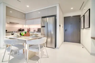 a kitchen with a table and chairs and a refrigerator at Seaside Splendor: Luxe Retreat at Emaar Beachfront in Dubai