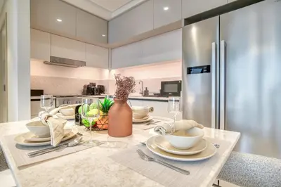 a kitchen with a table with dishes and a refrigerator at Seaside Splendor: Luxe Retreat at Emaar Beachfront in Dubai