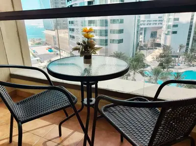 a table with a vase with a flower on a window at JBR Retreat: Stylish Views in Dubai
