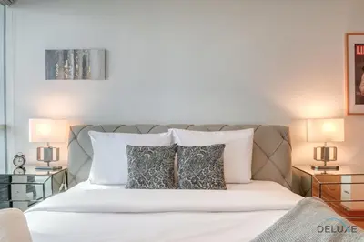 a bedroom with a white bed with two lamps at Contemporary 1BR at Marina Terrace Tower Dubai Marina by Deluxe Holiday Homes in Dubai
