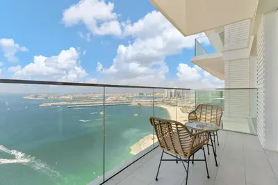 a balcony with two chairs and a table and the ocean at Maison Privee - Upscale Apt w/ Open Sea and Bluewaters Vws in JBR in Dubai