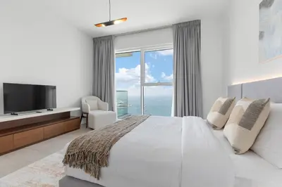 a white bedroom with a large bed and a television at Maison Privee - Upscale Apt w/ Open Sea and Bluewaters Vws in JBR in Dubai