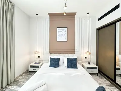 a bedroom with a large white bed with blue pillows at Trophy - Stardust Sanctum Suites w Pool view in Heart of JVC in Dubai